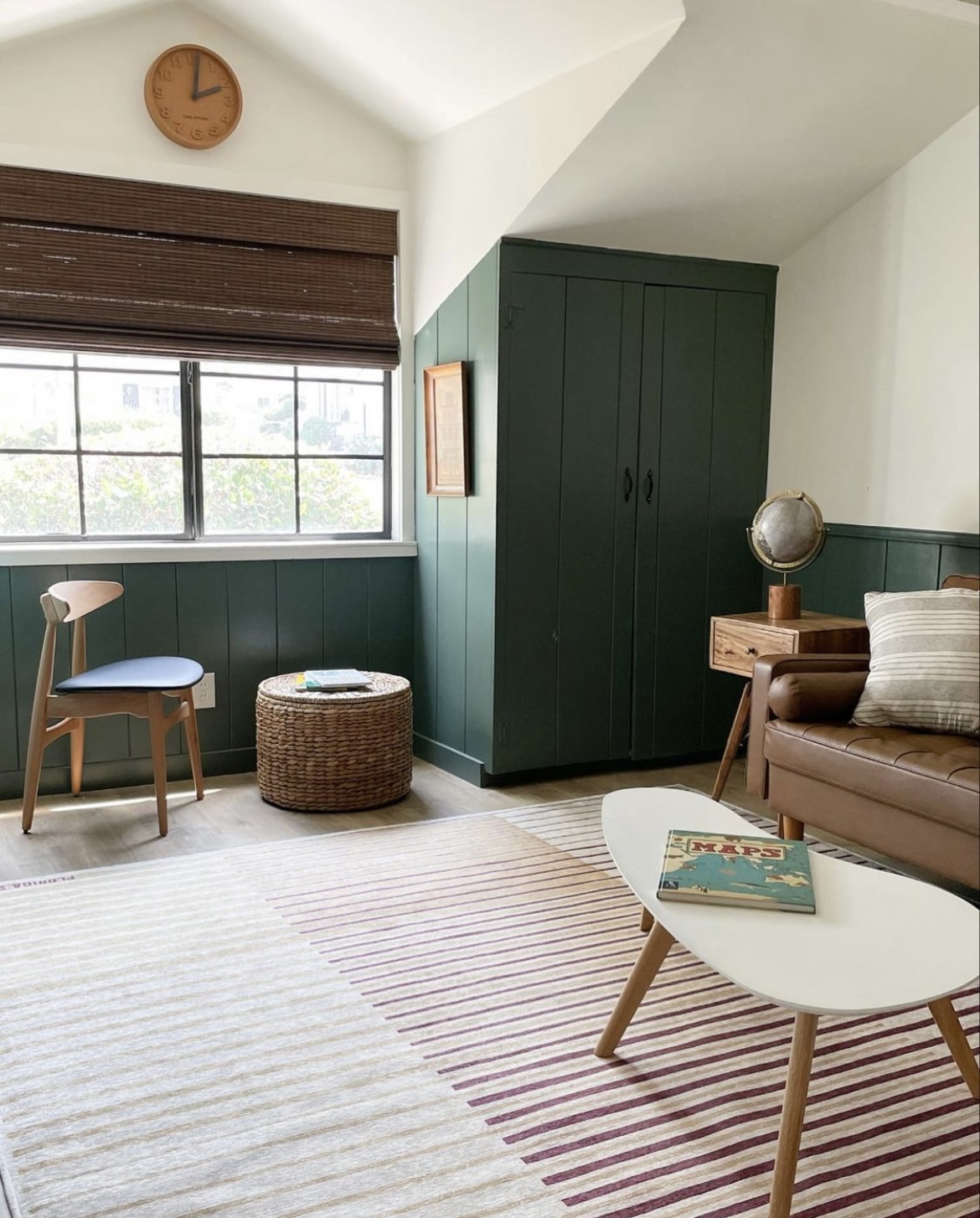 vertical shiplap, green paint, green playroom, kids playroom, wooden woven shades, 1950 beach cottage, modern traditional home, wicker ottoman, globe, brown leather couch, modern coffee table, shared kids bedroom, playroom ideas, playroom inspo