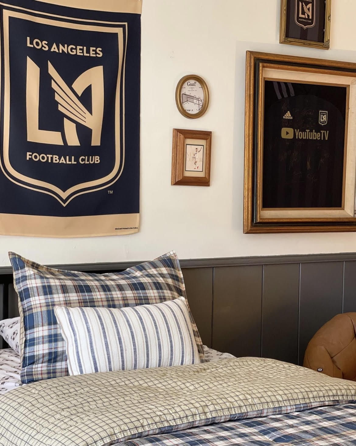 Boys soccer room, kids soccer themed room, kendall charcoal benjamin moore, dark gray paint, black paint, shiplap walls, dunn edwards swiss coffee paint, built in closets, window in middle of closet, wooden woven shades, interior dormer window, vintage rug, laminate floors, plaid bedding, LAFC themed room, modern traditional kids room, shiplap wainscotting, camp themed room, framed jersey, framed t shirt, LAFC themed room