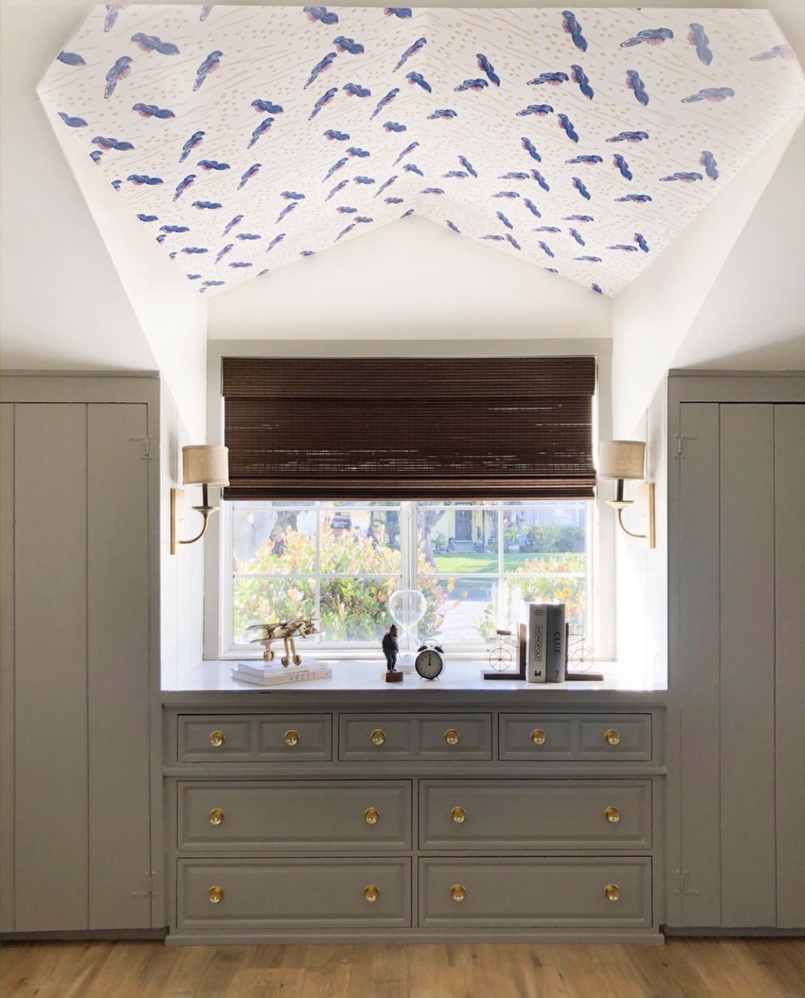 window and dresser in between closets, wallpapered ceiling, roman shades, wooden woven shades, built in dresser, gold sconces with shades, shiplap paneling, shiplap closets, rejuvenation hardware, kid's room inspiration, greige paint color, interior dormer window