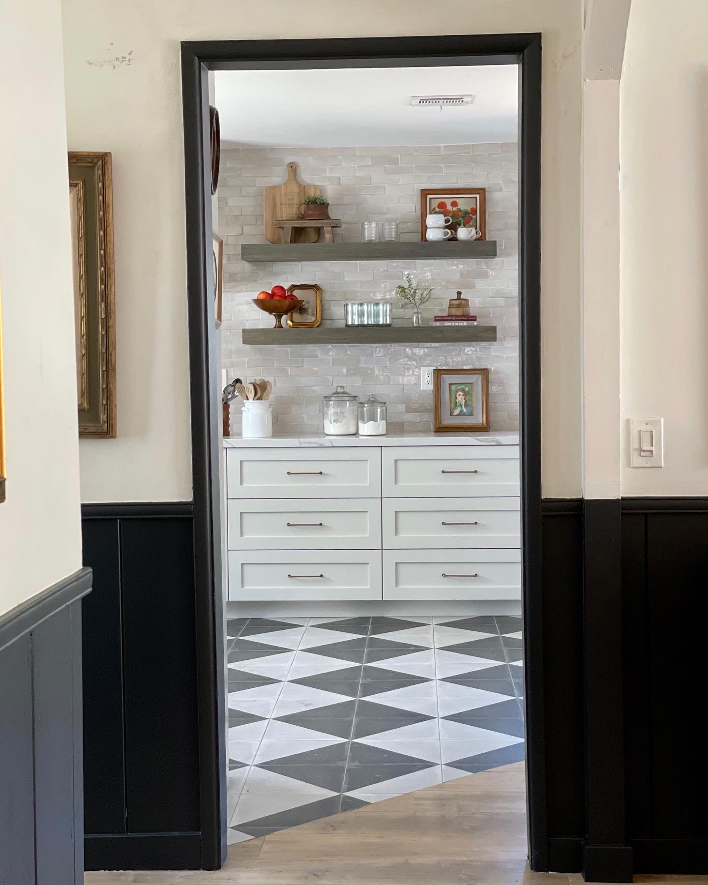 checkered floors, laminate wood floors, black wainscoting, mopboard black by benjamin moore, shiplap wainscoting, swiss coffee paint, modern farmhouse, art placement, modern traditional home, black paint colors, painted trim, painted wainscoting, kitchen floating shelves, styling floating shelves, paint transition