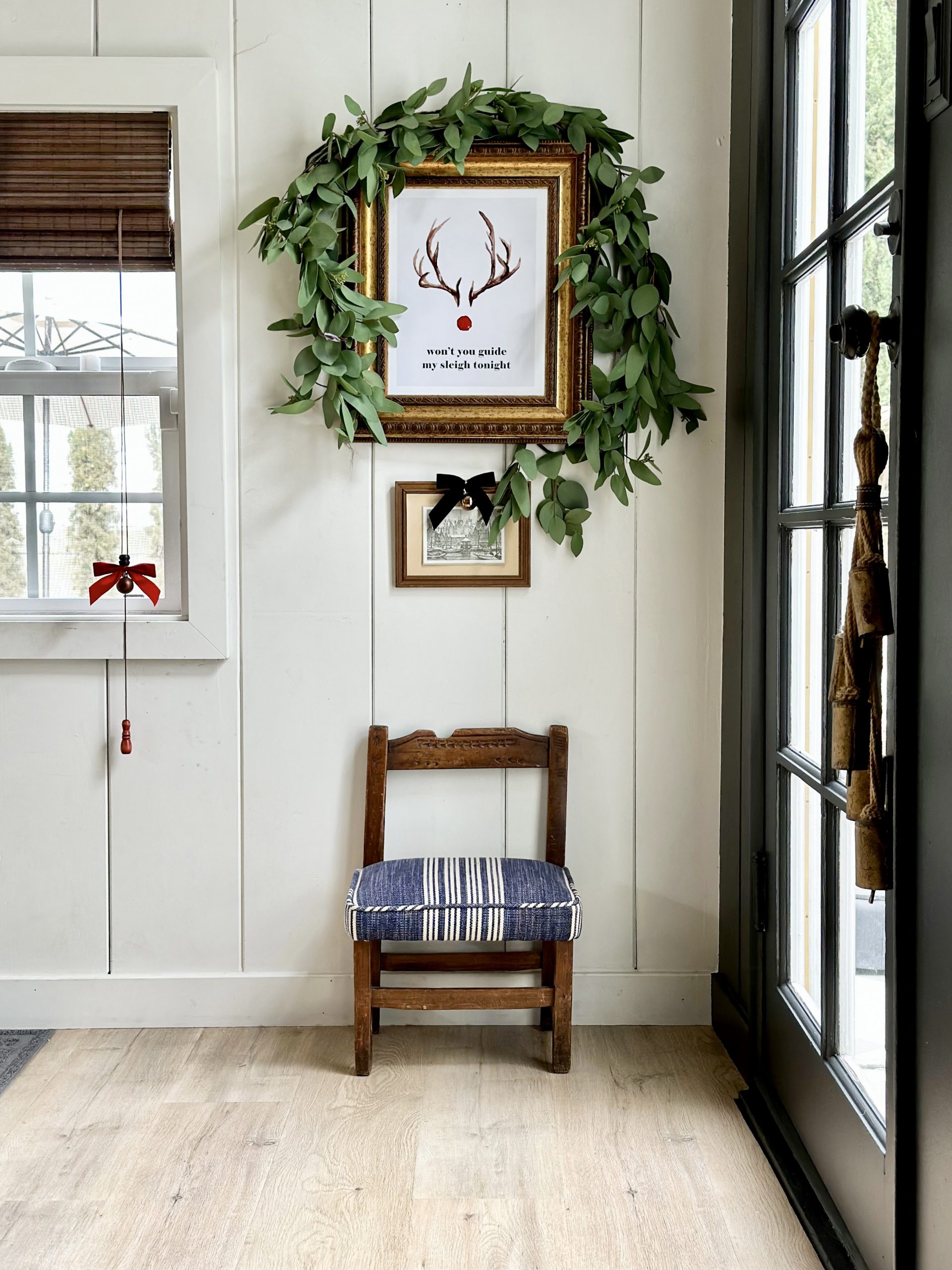 easy and budget friendly ways to decorate for christmas, decorating with bows, decorating art for christmas, christmas decor ideas, bows on art, christmas art, decorating art for christmas, mopboard black benjamin moore, swiss coffee paint color, white paint color, bow in window, shiplap walls, thrifted christmas, bells on door, laminate floors