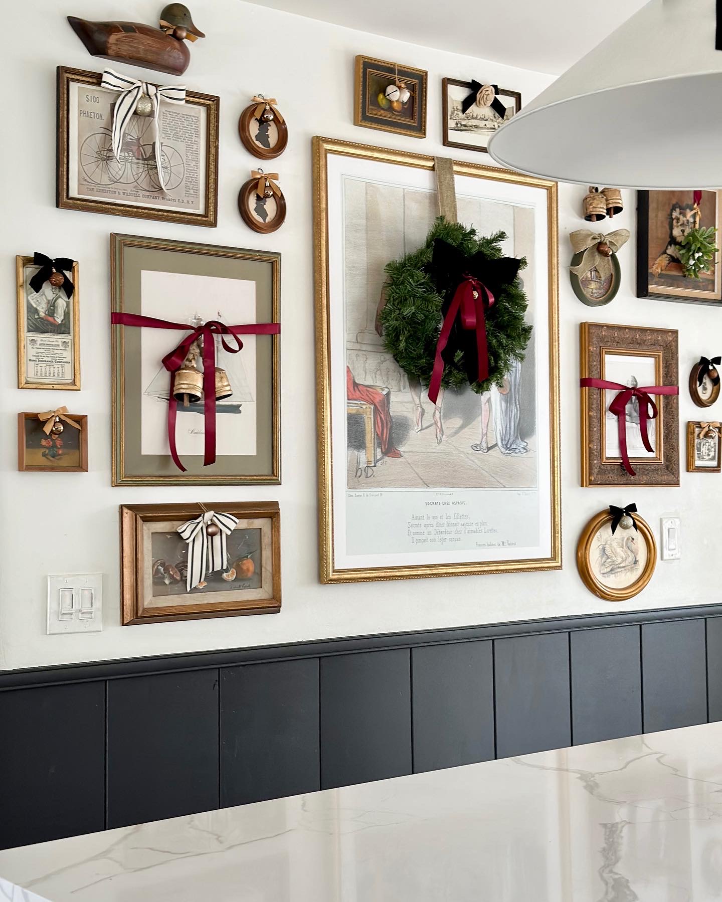 easy and budget friendly ways to decorate for christmas, decorating with bows, decorating art for christmas, christmas decor ideas, bows on frames, decorating art for christmas, christmas diy, framing wrapping paper, decorating gallery wall for christmas, bows on art, wreath on art, black wainscotting, decorating kitchen for christmas